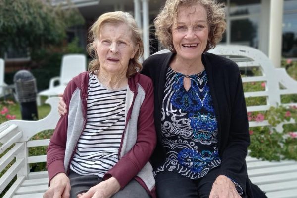 Lorraine sitting on garden seat with volunteer Marilyn